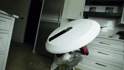 a person holding a surfboard in a kitchen with a stainless steel refrigerator in the background
