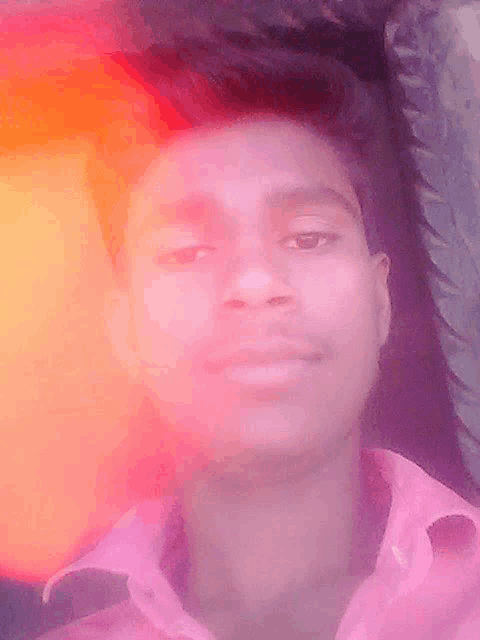 a young man in a pink shirt is taking a picture of himself