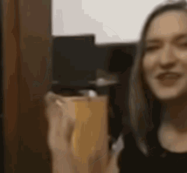 a woman in a black shirt is holding a glass of beer .