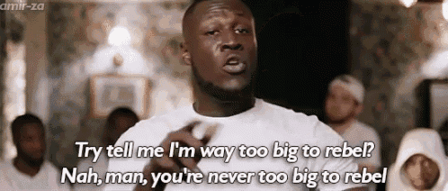 a man is saying " try tell me i 'm way too big to rebel " in front of a group of people