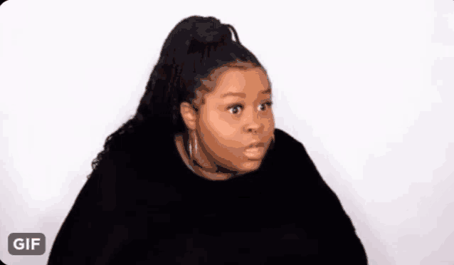 a woman is making a funny face while wearing a black sweater and earrings .