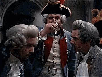 a man in a pirate hat is drinking from a glass while two other men look on