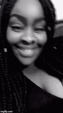 a black and white photo of a woman with braids smiling .
