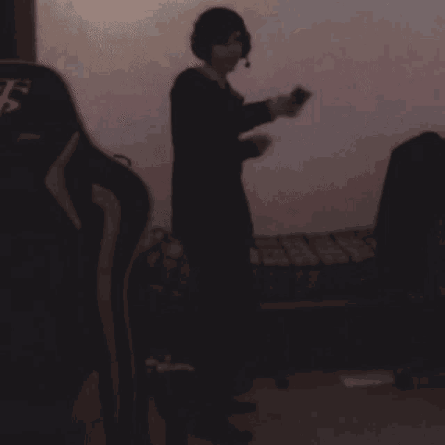 a person wearing headphones is standing in front of a chair with the letter f on the back