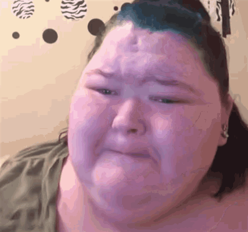 a very fat woman with blue hair is making a sad face