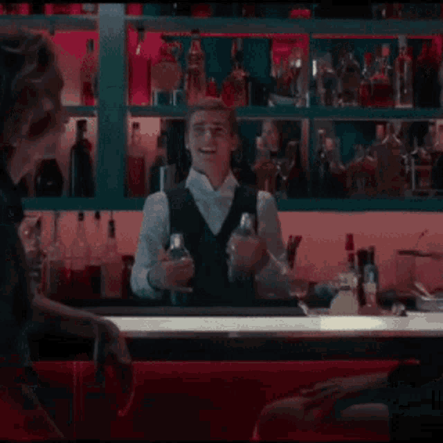 a bartender is making a drink in front of a shelf full of bottles