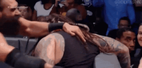 a man with dreadlocks is being hugged by another man in a wrestling ring .