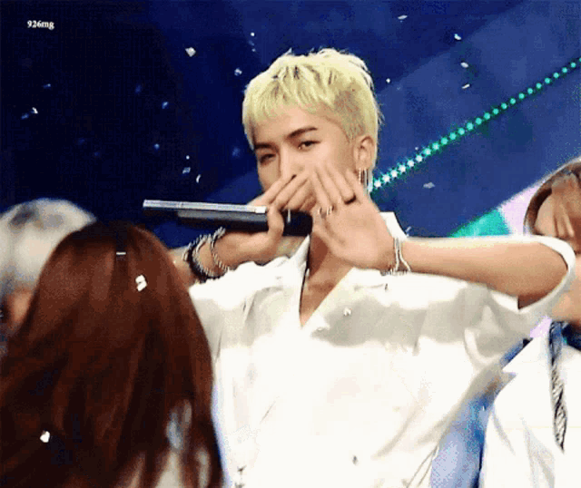 a man with blonde hair covering his mouth with his hands