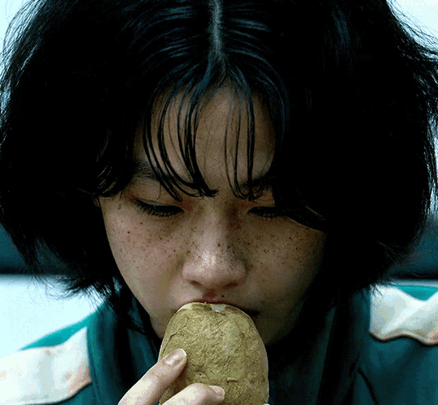 a close up of a woman eating a potato with her eyes closed