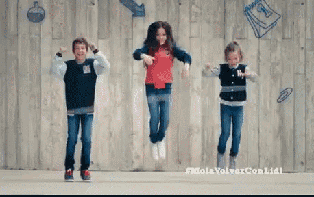 three kids are jumping in the air in front of a wooden wall