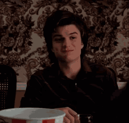 a man is sitting at a table with a plate and a fork and says it 's finger licking good .