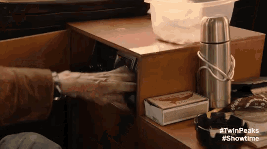 a box of cigarettes sits on a table next to a thermos and an ashtray ..