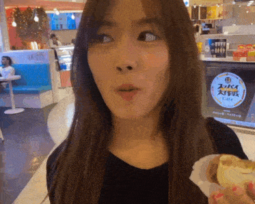 a woman eating a sandwich in front of a sign that says cafe on it