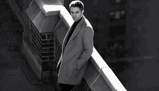 a black and white photo of a man standing on a ledge