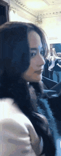 a close up of a woman 's face in a room with a crowd behind her