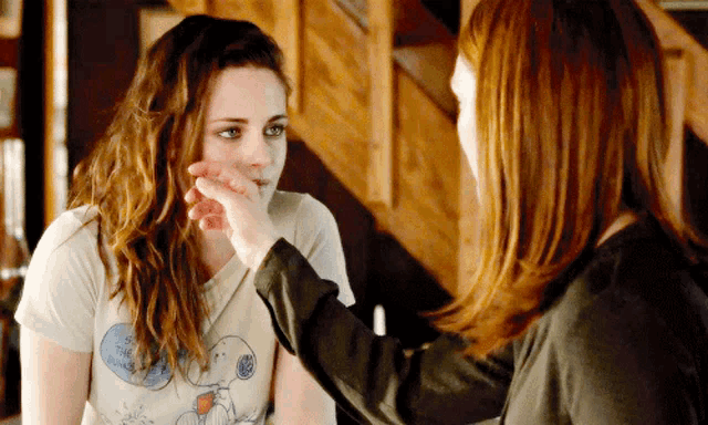 a woman touching another woman 's face with a shirt that says snoopy on it