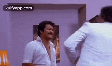 a man in a white shirt is standing next to another man in a white jacket .