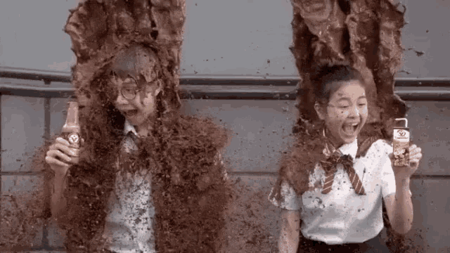a boy and a girl are covered in chocolate while holding a bottle .