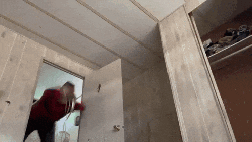 a person in a red shirt is opening a door in a room
