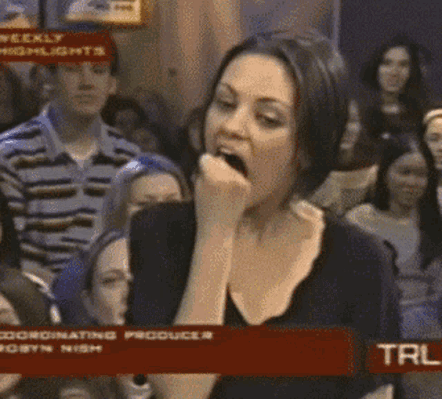 a woman with her hand in her mouth in front of a sign that says weekly highlights