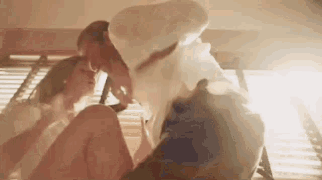 a man and a woman are kissing in bed .