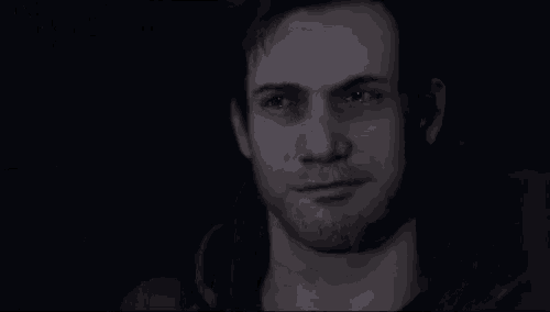 a man with a beard is smiling in a dark room in a video game .