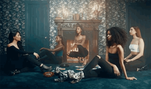 a group of women sit around a fireplace