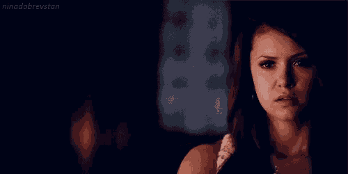 a close up of a woman 's face in a dark room with the name nina dobrevstan written on the bottom