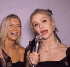 a woman is holding a microphone next to another woman .