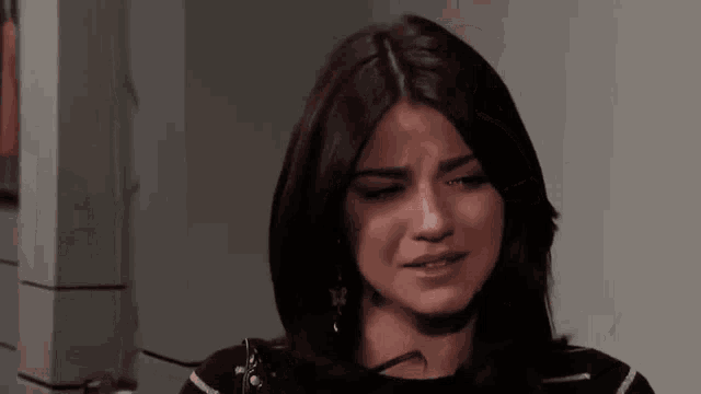 a woman is crying with her eyes closed in a dark room .