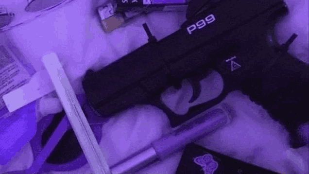 a black gun is sitting on top of a purple blanket next to a lighter .