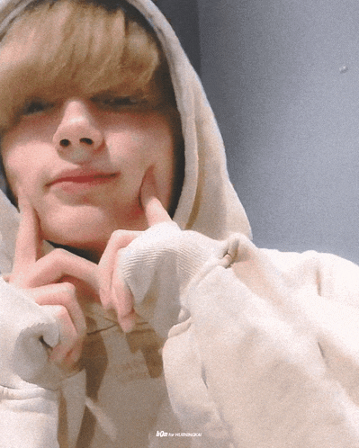 a person wearing a white hoodie has their fingers on their face and the letters ace are on the bottom right