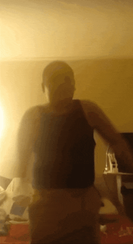 a man in a black tank top is standing in a room