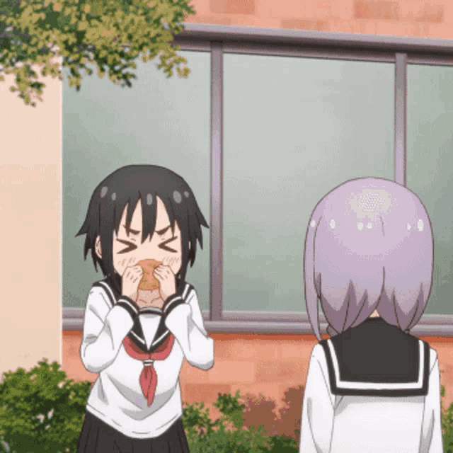 a girl with purple hair is eating a sandwich next to another girl