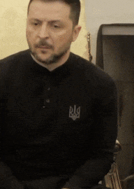 a man with a beard is wearing a black shirt with the letter lg on the front