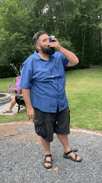 a man in a blue shirt is drinking a beer