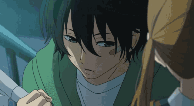 a boy with long black hair looks down at something