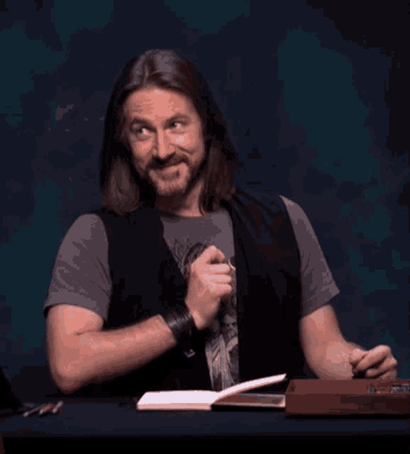 a man with long hair and a beard sits at a table