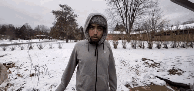 a man in a grey nike hoodie stands in the snow