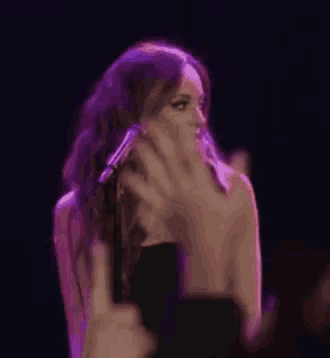a woman in a black dress is standing in front of a microphone and giving the middle finger .