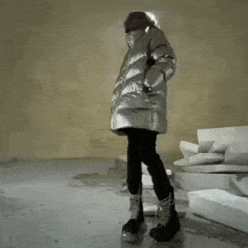 a person in a silver jacket is holding a toy airplane .