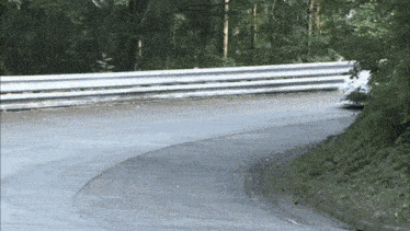 a car is going down a curvy road with a white railing