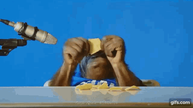 a man is eating chips in front of a microphone .