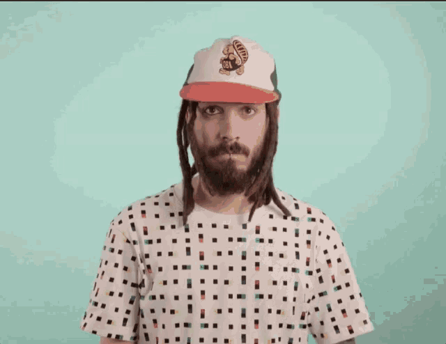 a man with dreadlocks is wearing a hat with a turtle on it and a polka dot shirt