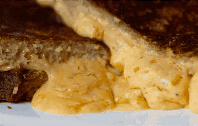 a grilled cheese sandwich with a bite taken out of it on a white plate
