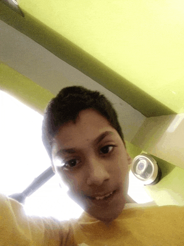 a young boy taking a selfie with a camera in the background