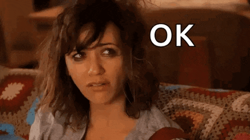a woman is sitting on a couch with her hair blowing in the wind and the words `` ok hot mess '' above her .
