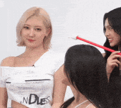 a woman wearing a white shirt that says endless stands next to two other women