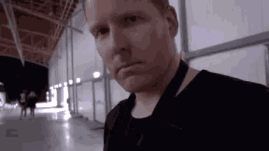 a man wearing a black shirt and a lanyard is standing in a building .