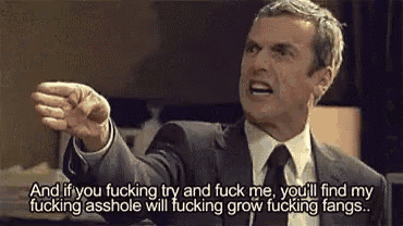 a man in a suit and tie is making a funny face and pointing his finger .